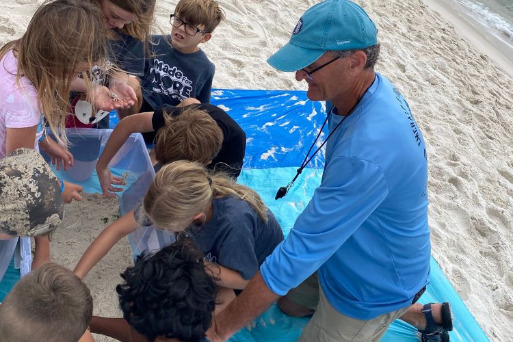 Volunteer showing students creatures in a touch tank