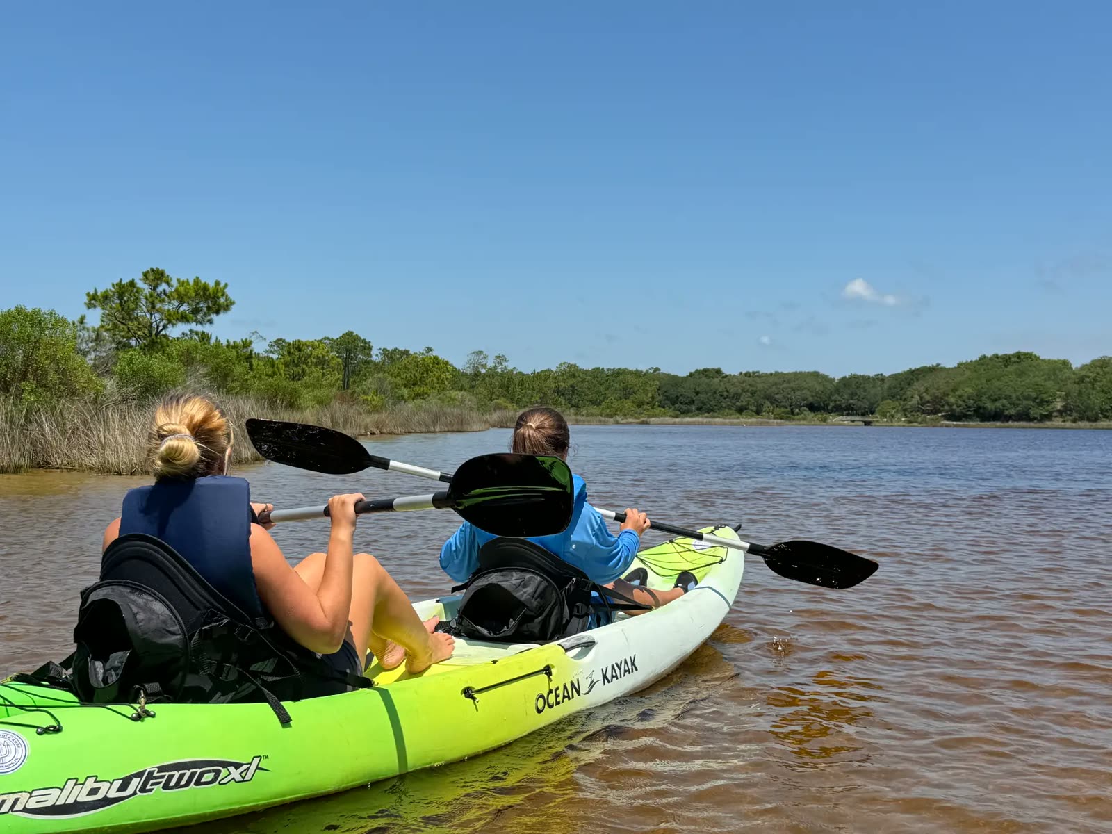 Campers kayaking across a coastal dune lake
