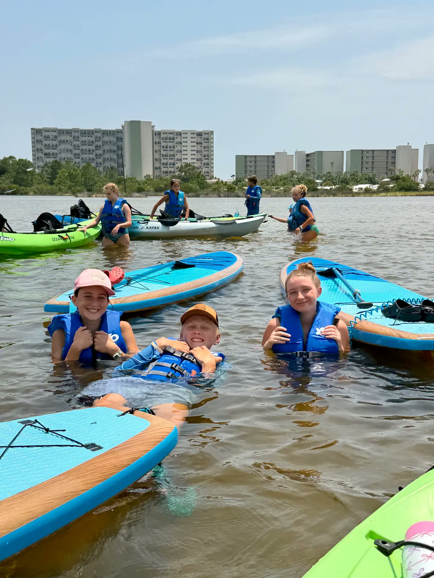 Campers cooling off beside paddleboards and kayaks on the lake