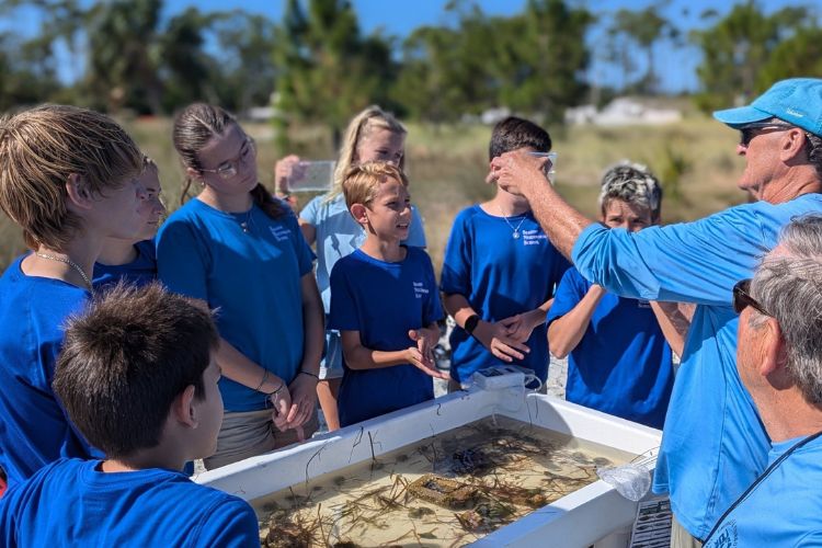 Students gathered around a touch tank with an educator
