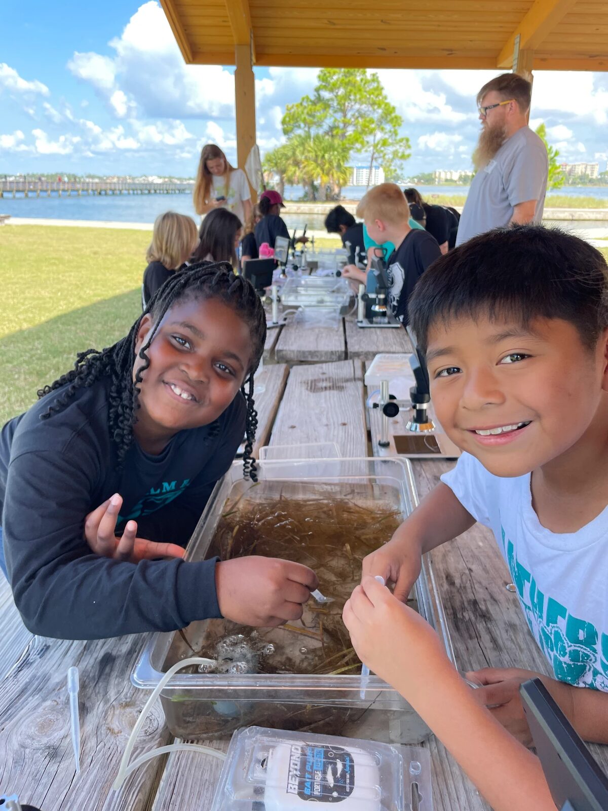 Two students examining seagrass samples at a sorting tray
